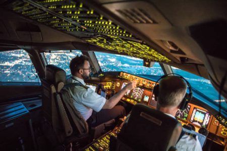 Two pilots at work during departure of Dallas Fort Worth Airport in United States of America. The view from the flight deck with high workload the beginning night through the wind shield